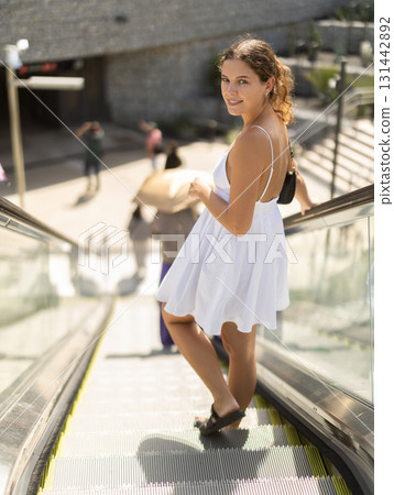Woman standing on escalator on a sunny day 131442892