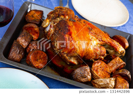 Appetizing baked pork ham and potatoes served on baking sheet Appetizing baked pork ham and potatoes served on baking sheet 131442896