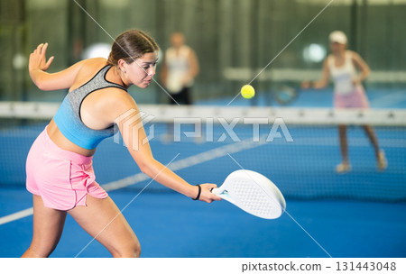 Young woman playing tennis against man and woman 131443048