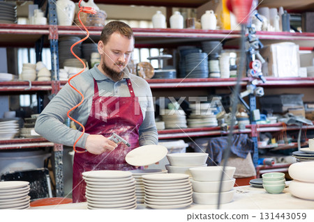 Young man paints blanks of ceramic products Young man paints blanks of ceramic products 131443059