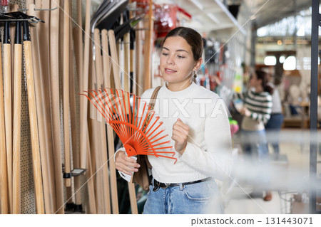 Adult woman choosing rake in store 131443071