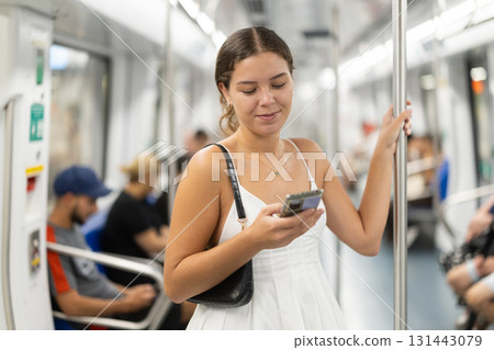 Positive young girl standing on wagon holding phone in hand 131443079