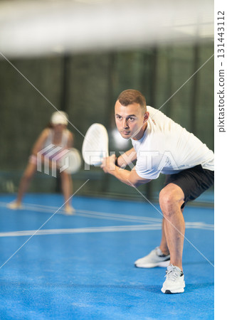 Young man and adult woman playing doubles tennis 131443112