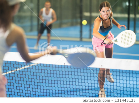 Young woman and man playing tennis against woman 131443125