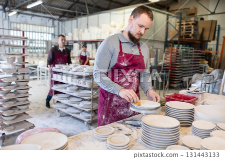 Young man cleaning blanks of ceramic products 131443133