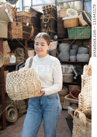 Young woman choosing basket in store Young woman choosing basket in store 131443179