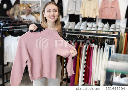 Young woman choosing pullover in clothing store 131443204