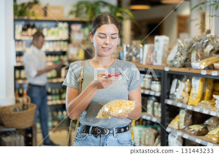 Woman scanning barcode on pasta package for mobile payment in store Woman scanning barcode on pasta package for mobile payment in store 131443233