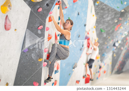 Sporty woman training at bouldering gym without special climbing equipment 131443244