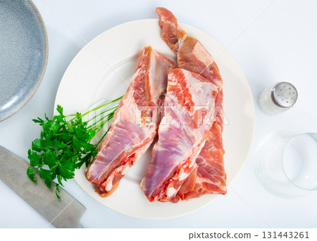 Fresh pork ribs on white ceramic plate with parsley on table Fresh pork ribs on white ceramic plate with parsley on table 131443261