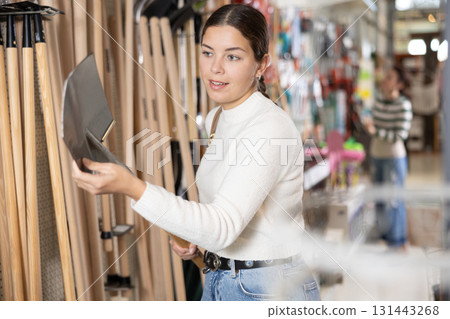 Amateur gardener girl selects necessary items tools for her hobby in greenhouse flower-bed Amateur gardener girl selects necessary items tools for her hobby in greenhouse flower-bed 131443268