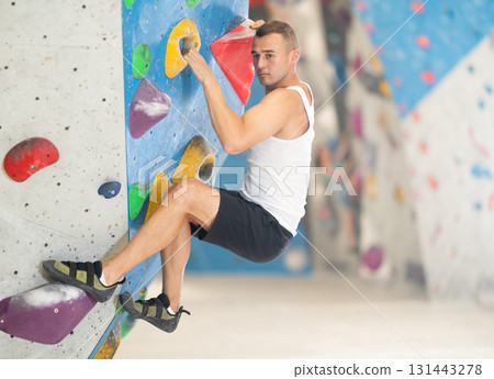Sporty man in doing difficult wall climb in climbing gym without special climbing equipment Sporty man in doing difficult wall climb in climbing gym without special climbing equipment 131443278