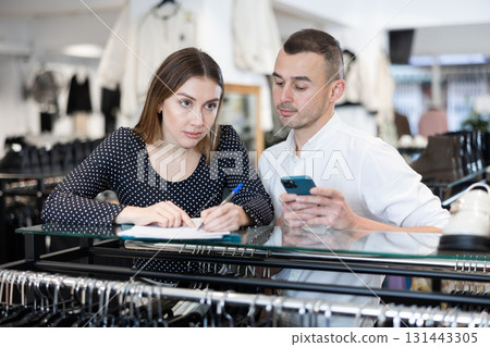 Man with phone in hands participates in discussion of business development plans with wife Man with phone in hands participates in discussion of business development plans with wife 131443305