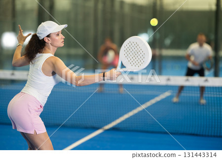 Adult woman playing tennis against man and woman 131443314