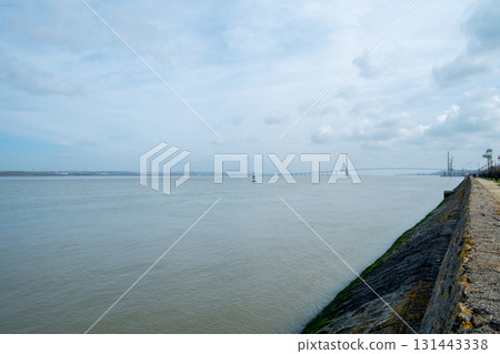 Tranquil and Calm River Scene with Distant Structures Framed by a Cloudy Sky Above Tranquil and Calm River Scene with Distant Structures Framed by a Cloudy Sky Above 131443338