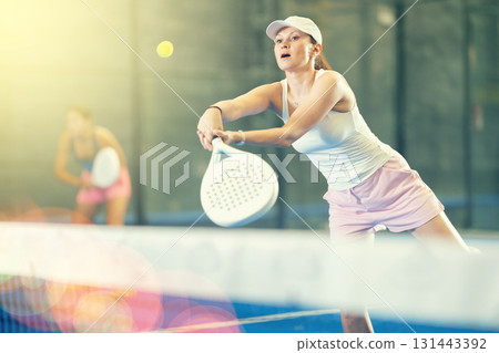 Woman playing padel on indoor court on summer day. Sport and active lifestyle concept 131443392