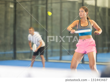 Young woman and man playing doubles tennis Young woman and man playing doubles tennis 131443487