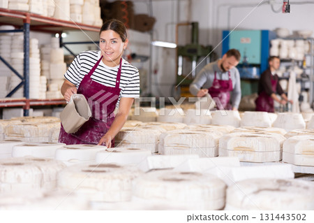 Female artisan pouring slip into casting molds in workshop Female artisan pouring slip into casting molds in workshop 131443502