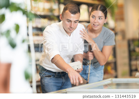 Man with package of eggs in hands talks with wife about buying ingredients for making homemade pie. 131443519