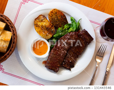 Roasted beef steak in chimichurri sauce served with baked potatoes. Spanish cuisine 131443546