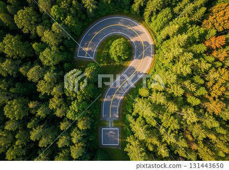 An aerial view shows a road forming a question mark surrounded by lush green forest. The unique winding path is embedded in dense trees, creating a striking visual contrast from above against the natu An aerial view shows a road forming a question mark surrounded by lush green forest. The unique winding path is embedded in dense trees, creating a striking visual contrast from above against the natu 131443650