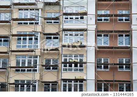 Residential building facade under construction with new windows and scaffolding. 131444165