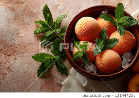 Peach sorbet served in a wooden bowl with fresh mint leaves 131444283