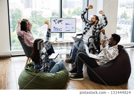 Group of diverse colleagues celebrating project success in office. Includes people of different backgrounds, one using wheelchair, sharing excitement and teamwork. Group of diverse colleagues celebrating project success in office. Includes people of different backgrounds, one using wheelchair, sharing excitement and teamwork. 131444824