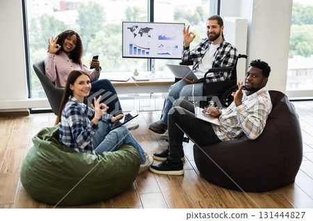 Diverse group of young adults collaborating in modern office setting. Individuals using laptops, discussing projects, promoting inclusion, productivity, teamwork. Diverse group of young adults collaborating in modern office setting. Individuals using laptops, discussing projects, promoting inclusion, productivity, teamwork. 131444827
