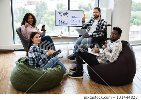 Young adults of different genders and ethnicities working together with laptops, happy, casual 131444828