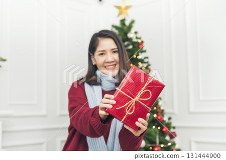 Woman surprise got present gift box on christmas eve. Asian woman holding christmas gift box under xmas tree with smiling face. Woman hands wrap present gift. Merry christmas happy new year concept Woman surprise got present gift box on christmas eve. Asian woman holding christmas gift box under xmas tree with smiling face. Woman hands wrap present gift. Merry christmas happy new year concept 131444900