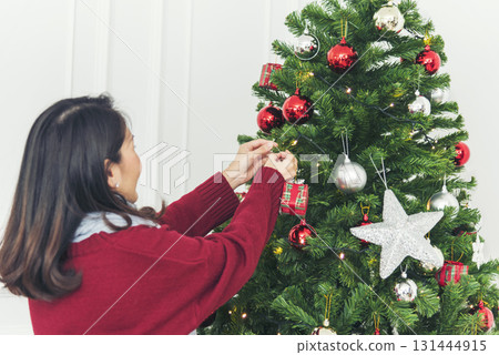 Woman hands decorate Christmas tree red ball, bauble, snow flake. Close up hands holding red ball bauble decorate. Asian woman decor bauble ball christmas tree in xmas holiday winter season celebrate 131444915