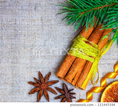 A Christmas photo shows cinnamon sticks and star anise with a spruce branch and dried orange 131445594