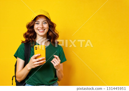 smiling young woman with backpack and mobile phone on yellow background, delivery service concept 131445951