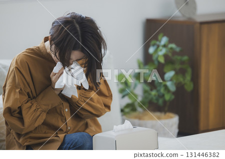 A woman with a cold blowing her nose 131446382