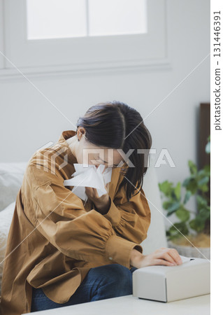 A woman with a cold blowing her nose 131446391