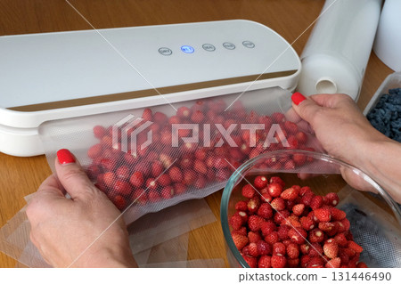 Vacuum sealer of strawberries, honeysuckle in bag, packaging for long-term storage . Vacuum packing machine 131446490