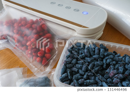 Vacuum sealer of strawberries, honeysuckle in bag, packaging for long-term storage . Vacuum packing machine 131446496