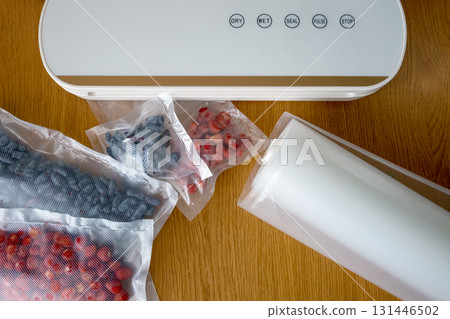 Vacuum sealer of strawberries, honeysuckle in bag, packaging for long-term storage . Vacuum packing machine 131446502