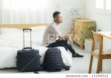 A foreign man looking at his smartphone in a hotel room 131446522