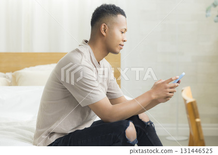 A foreign man looking at his smartphone in a hotel room 131446525