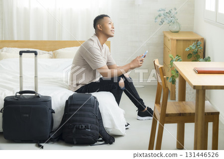A foreign man looking at his smartphone in a hotel room 131446526