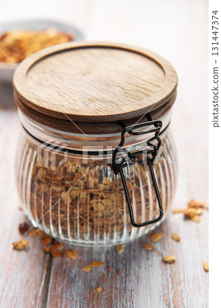 Glass jar holding healthy fresh homemade granola 131447374