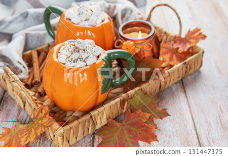 Pumpkin mugs with hot chocolate for autumn cozy warmth 131447375