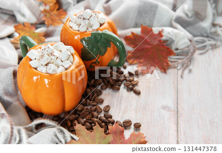 Pumpkin mugs with marshmallows, coffee beans, autumn leaves Pumpkin mugs with marshmallows, coffee beans, autumn leaves 131447378