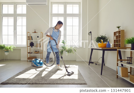 Cleaner, female homeowner tidying up at home, vacuuming carpet, floor in modern living room Cleaner, female homeowner tidying up at home, vacuuming carpet, floor in modern living room 131447901