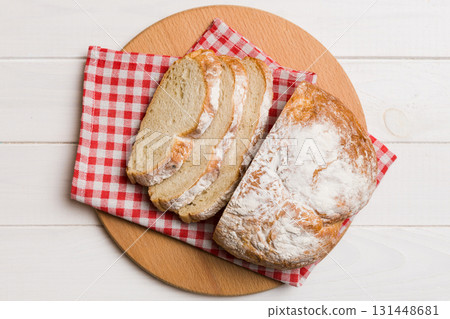 Freshly baked bread slices on cutting board against white wooden background. top view Sliced bread Freshly baked bread slices on cutting board against white wooden background. top view Sliced bread 131448681