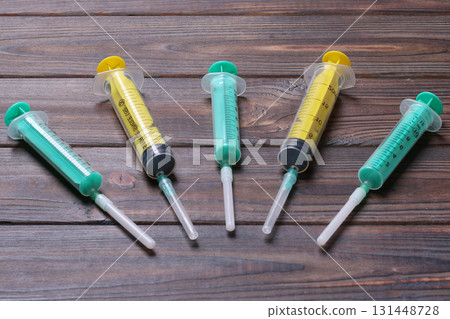 Top view of many syringes prepared for injection at wooden background. Treatment concept with copy space Top view of many syringes prepared for injection at wooden background. Treatment concept with copy space 131448728