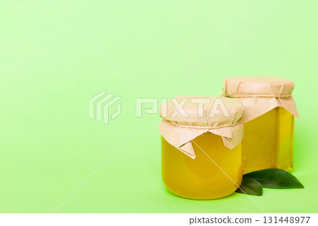 Honey in jar with leaves and honey dipper on colored background top view with copy text Honey in jar with leaves and honey dipper on colored background top view with copy text 131448977
