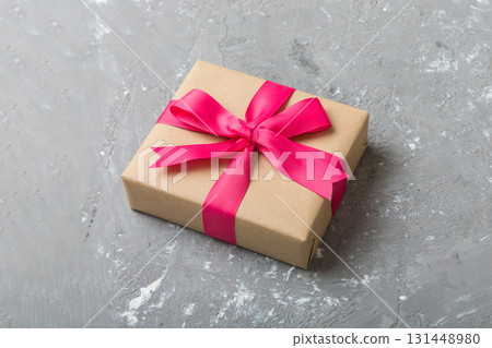 Wrapped christmas or other holiday handmade present in craft paper with colored ribbon. Present box, decoration of gift on table, top view with copy space 131448980